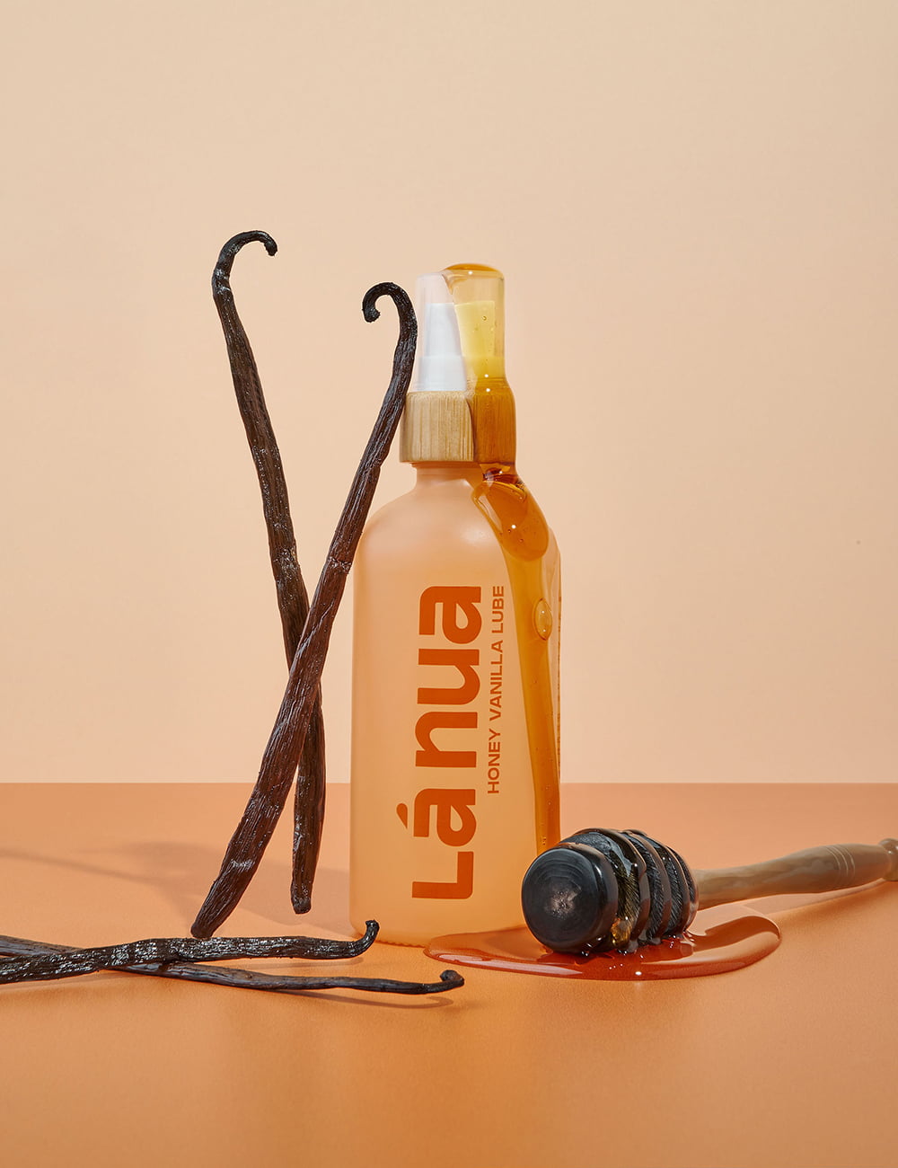 Lá Hua honey vanilla vegan lube bottle with vanilla beans and honey on a beige background