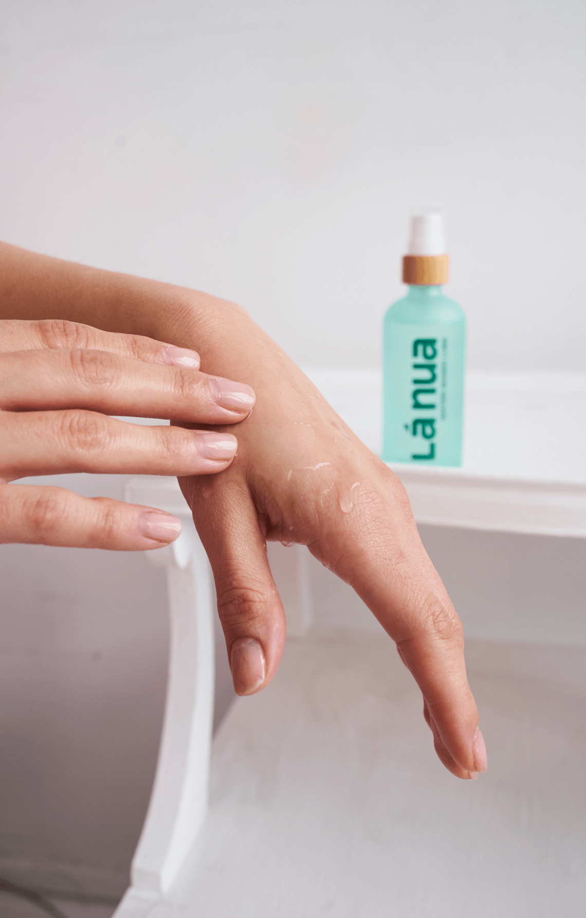 Person applying water-based lubricant to their hand with a bottle labeled 'La nua' in the background.