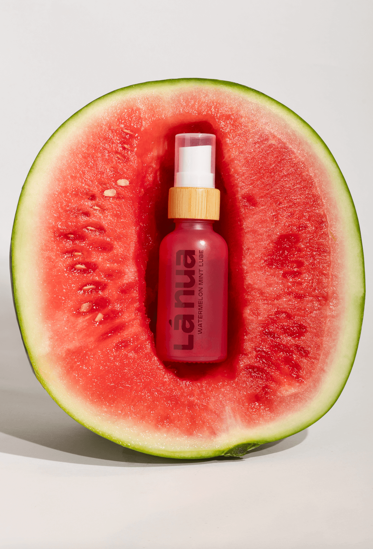 La nua flavored lube bottle inside a watermelon on a light background
