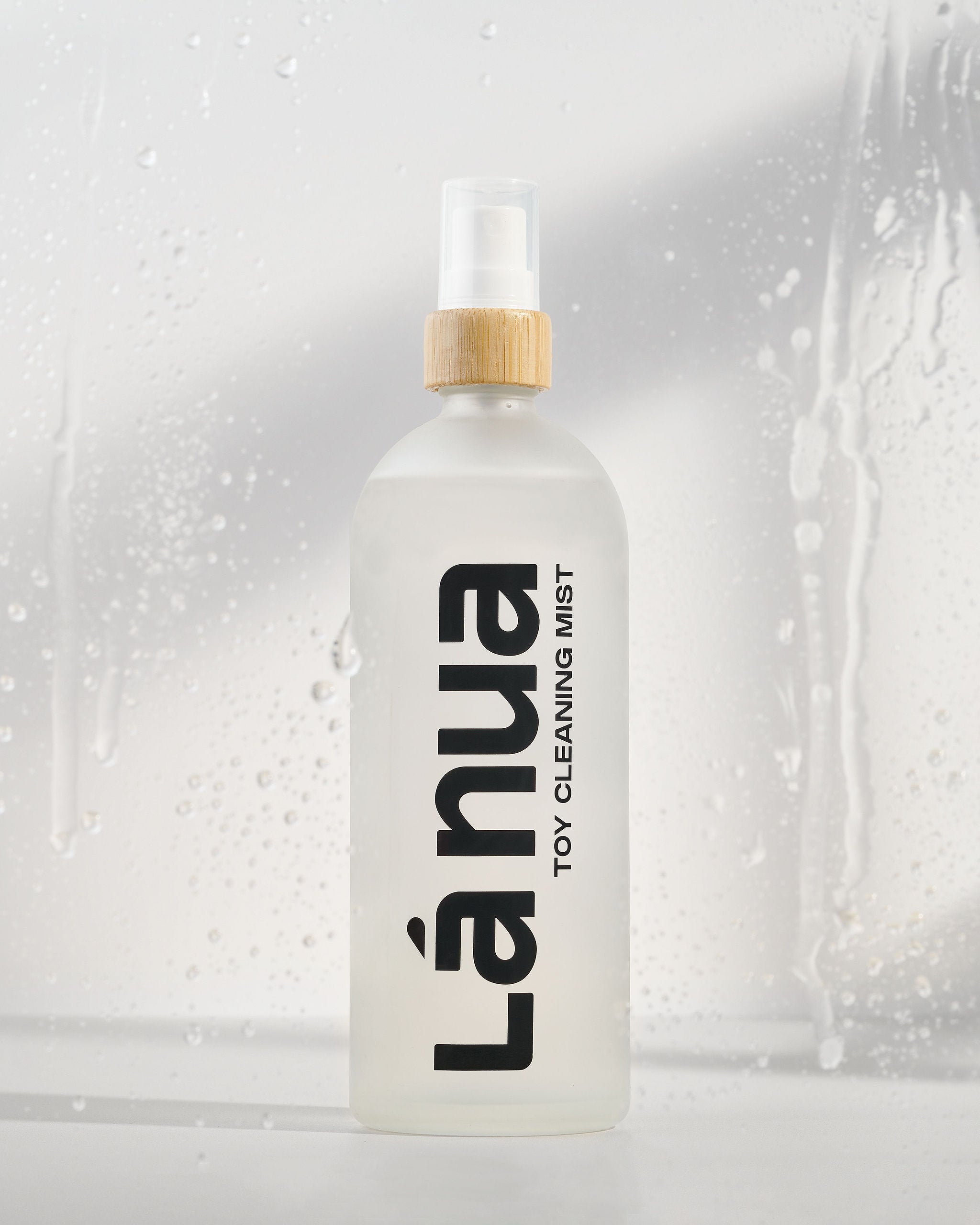 La nua toy cleaning mist bottle with a wooden cap on a light gray background.