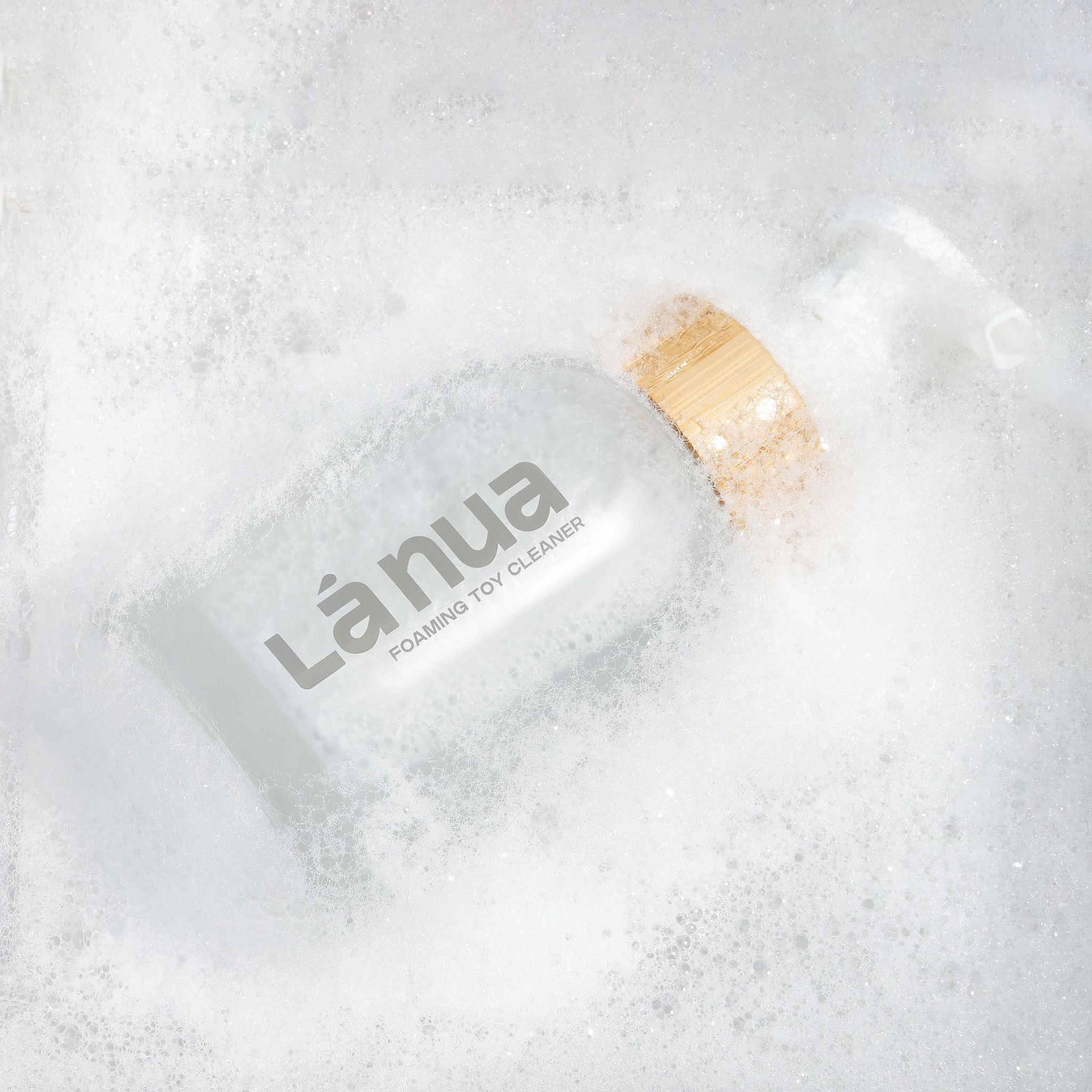 Bottle of Lánua foaming toy cleaner surrounded by bubbles on a white background