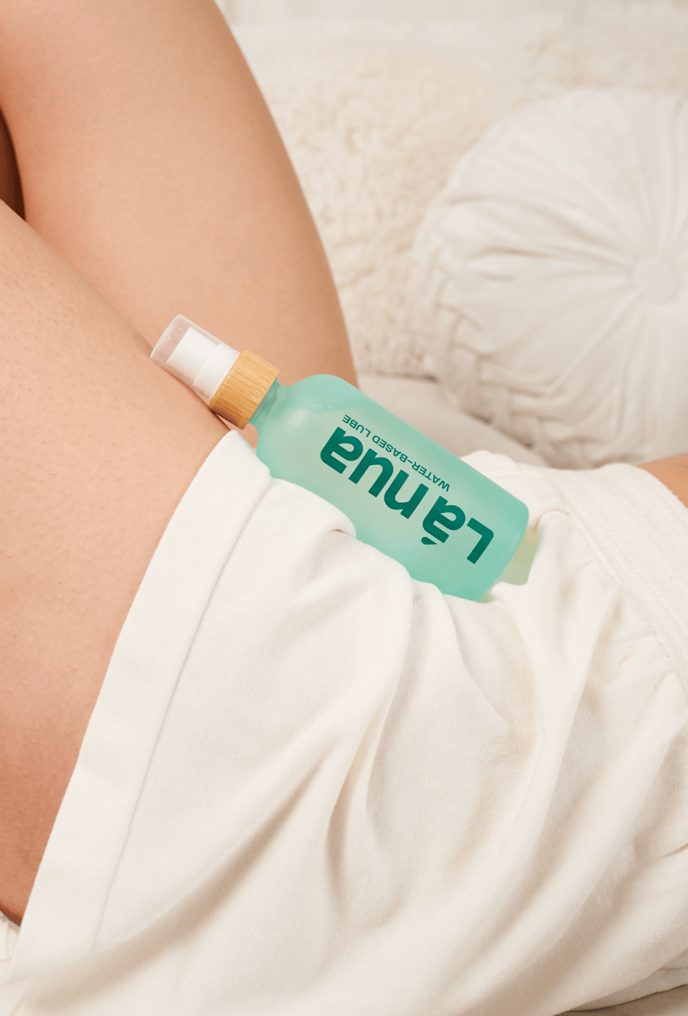 Person holding a green bottle of water-based lube labeled 'la nua' against a neutral background